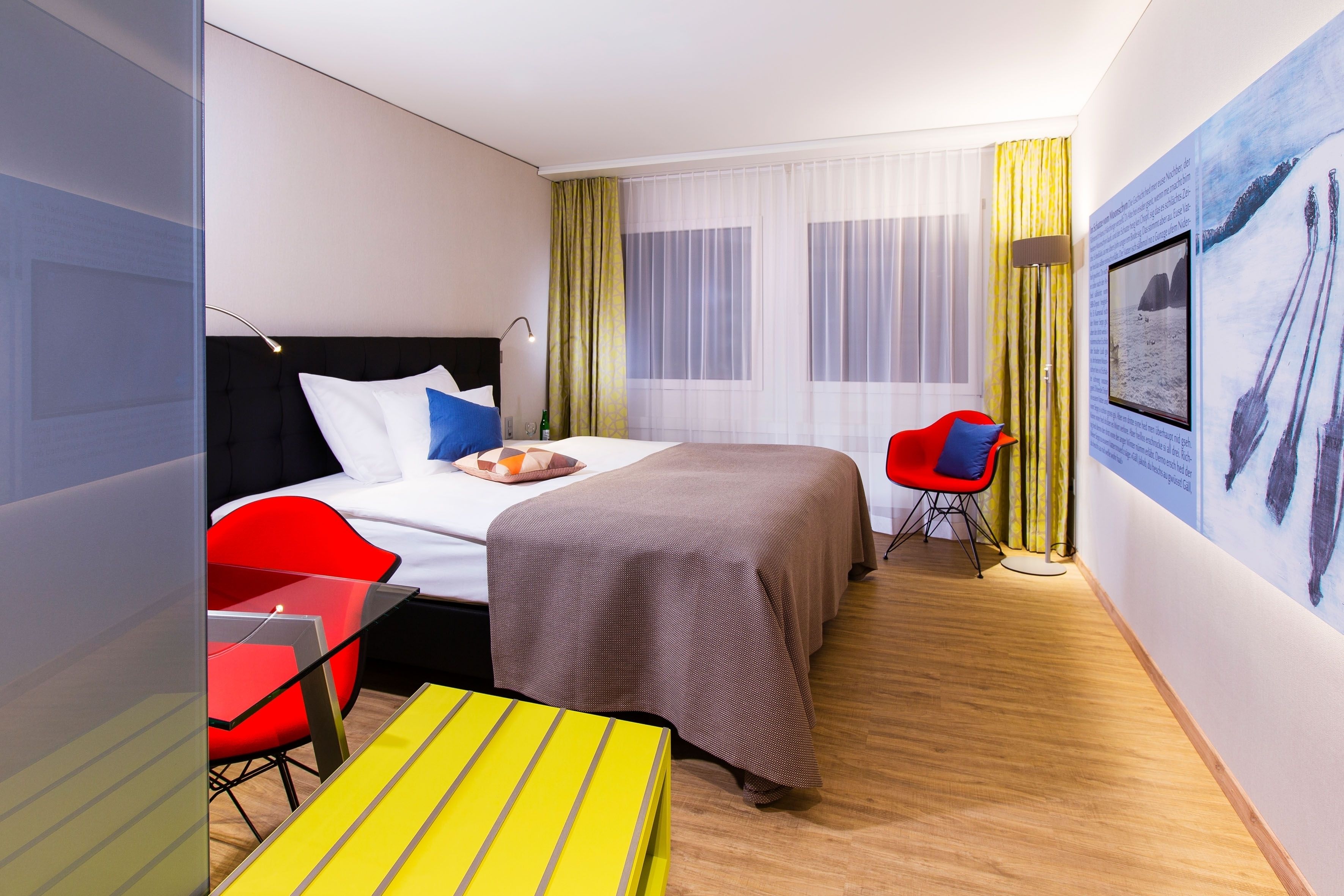 A hotel room with a bed, a desk, a chair, and a large window with curtains.