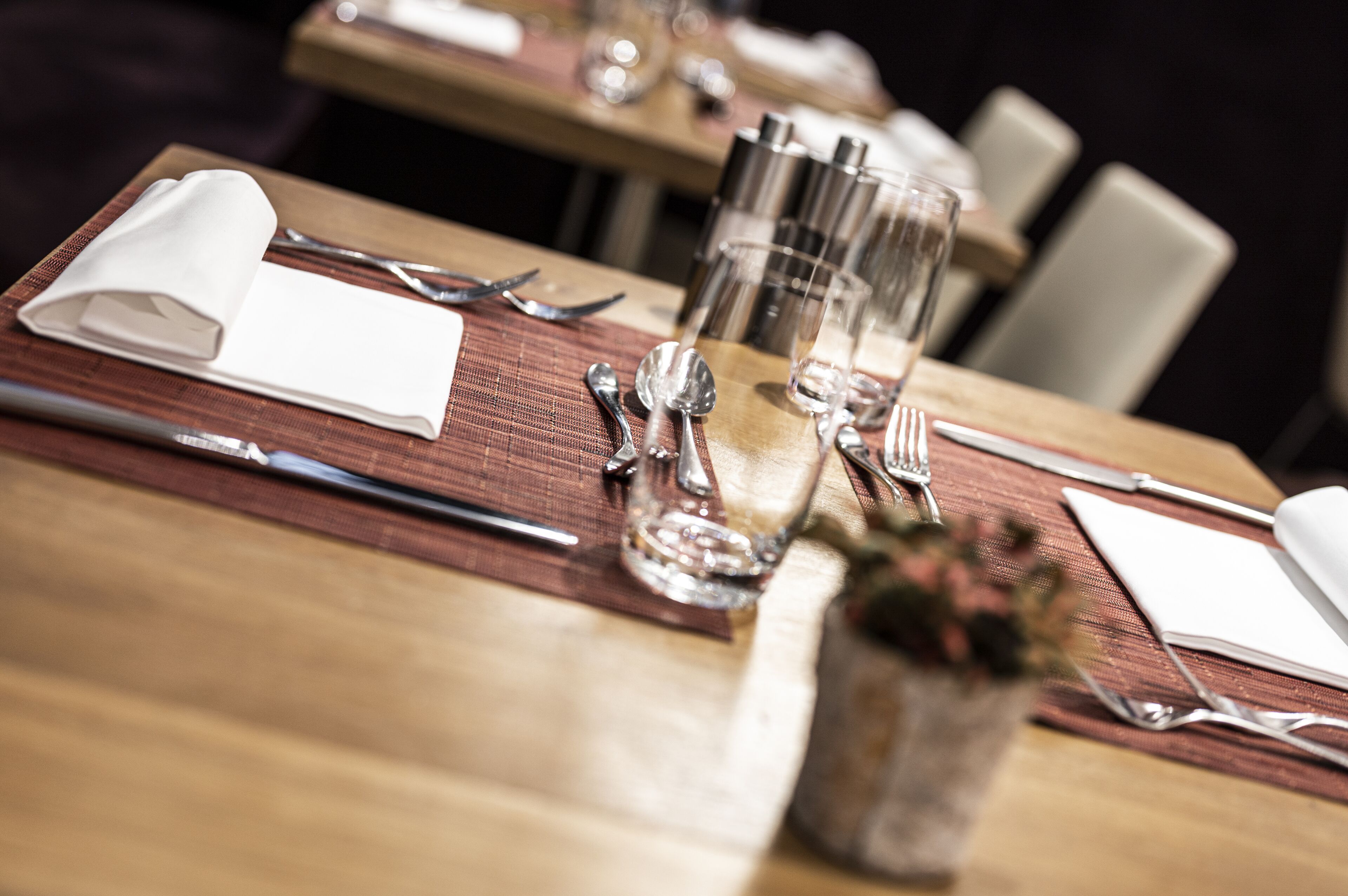 A dining table set with cutlery, glasses, and a napkin.