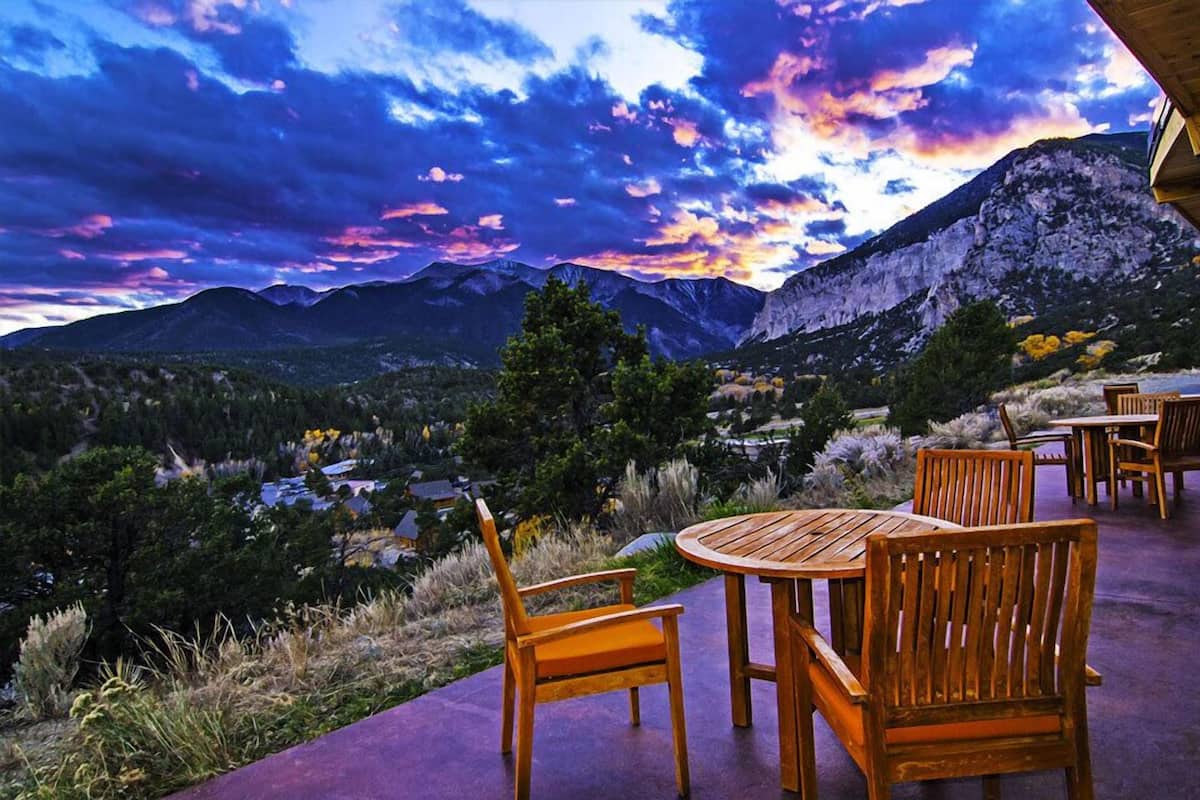 Un conjunto de mesa y sillas de madera al aire libre, con vistas a la montaña.
