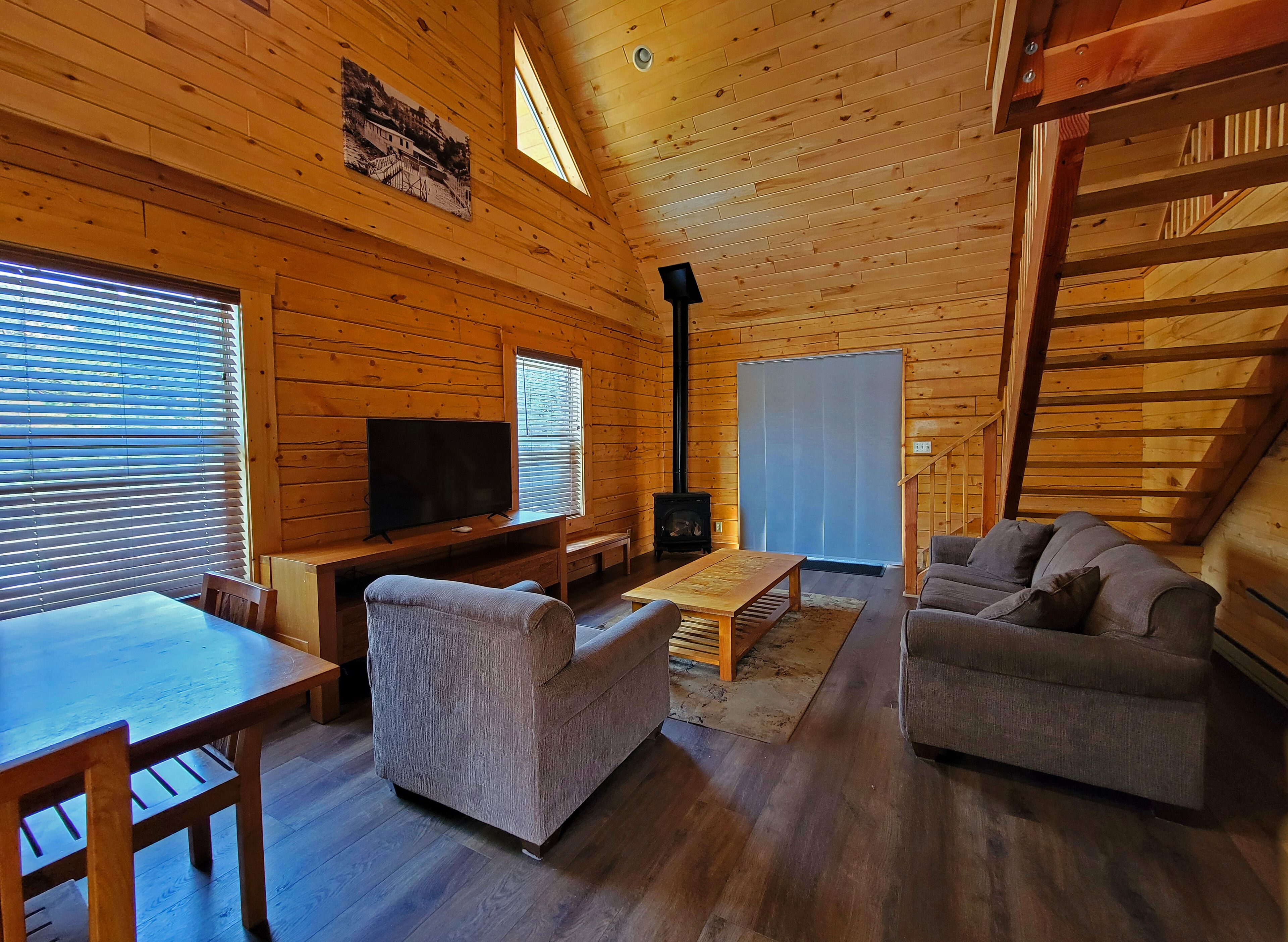 A wooden cabin interior with a TV, sofa, and fireplace.