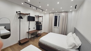Una habitación de hotel moderna con cama, escritorio, televisor y armario.