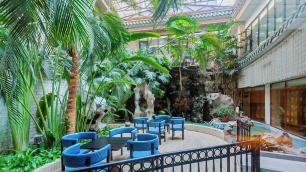 An indoor atrium with a tropical garden, seating area, and a waterfall feature. - New TianHe Hotel (Guangzhou)