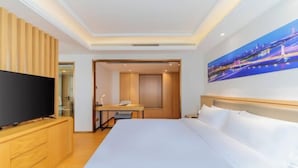A hotel room with a bed, a TV, a desk, and a painting on the wall. - New TianHe Hotel (Guangzhou)