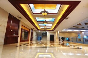 A hotel lobby with a central staircase, a reception desk, and a glass railing on the right. - Orient Haitian Guibin Hotel (Yantai)