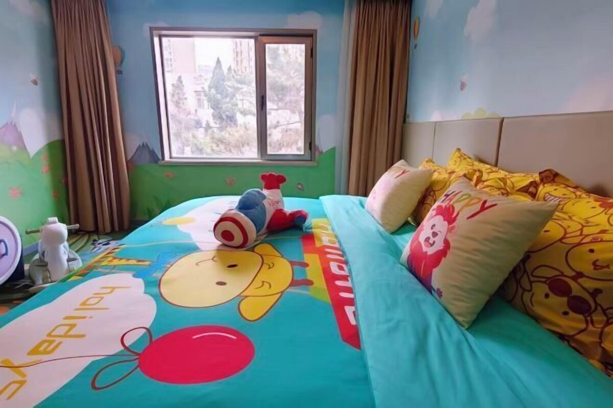 A child's room with a bed, pillows, a window, and a wall with a mountain design.