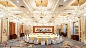 A conference room with a round table, white chairs, chandeliers, and a colorful carpet. - Orient Haitian Guibin Hotel (Yantai)
