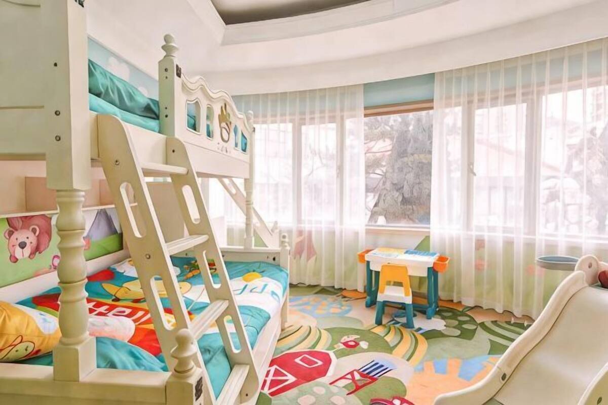 A child's bedroom with bunk beds, a desk, and a play area.