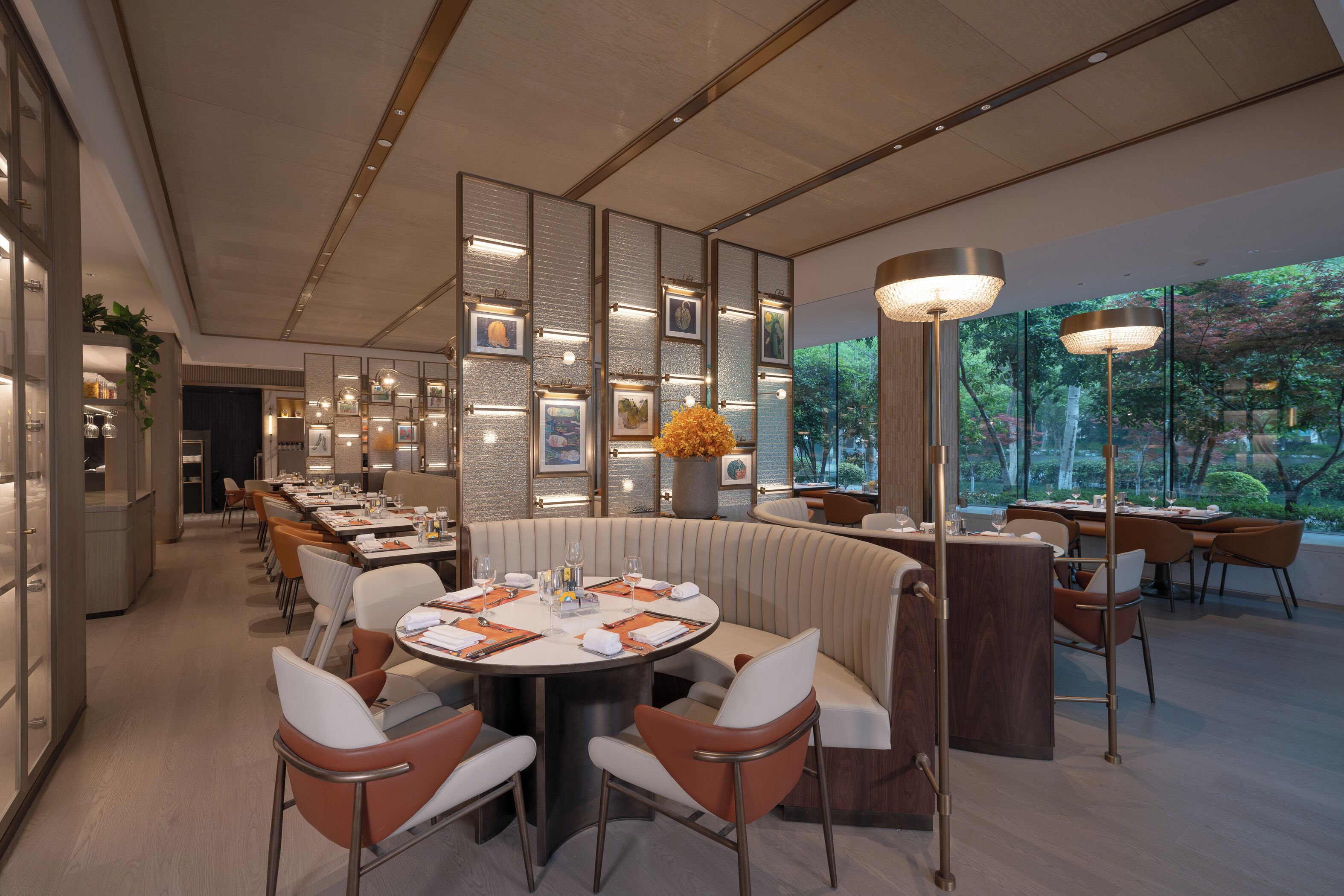 A modern restaurant with round tables, cushioned booths, and pendant lighting.
