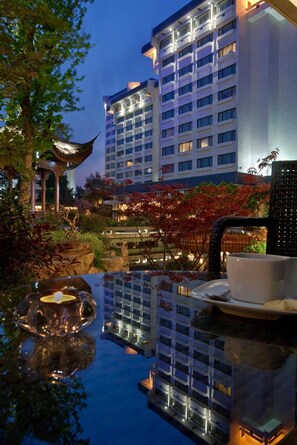 Ein Hotel mit einem traditionellen pagodengleichen Gebäude, einem Schwimmbad und einem Essbereich mit Tisch und Stühlen.