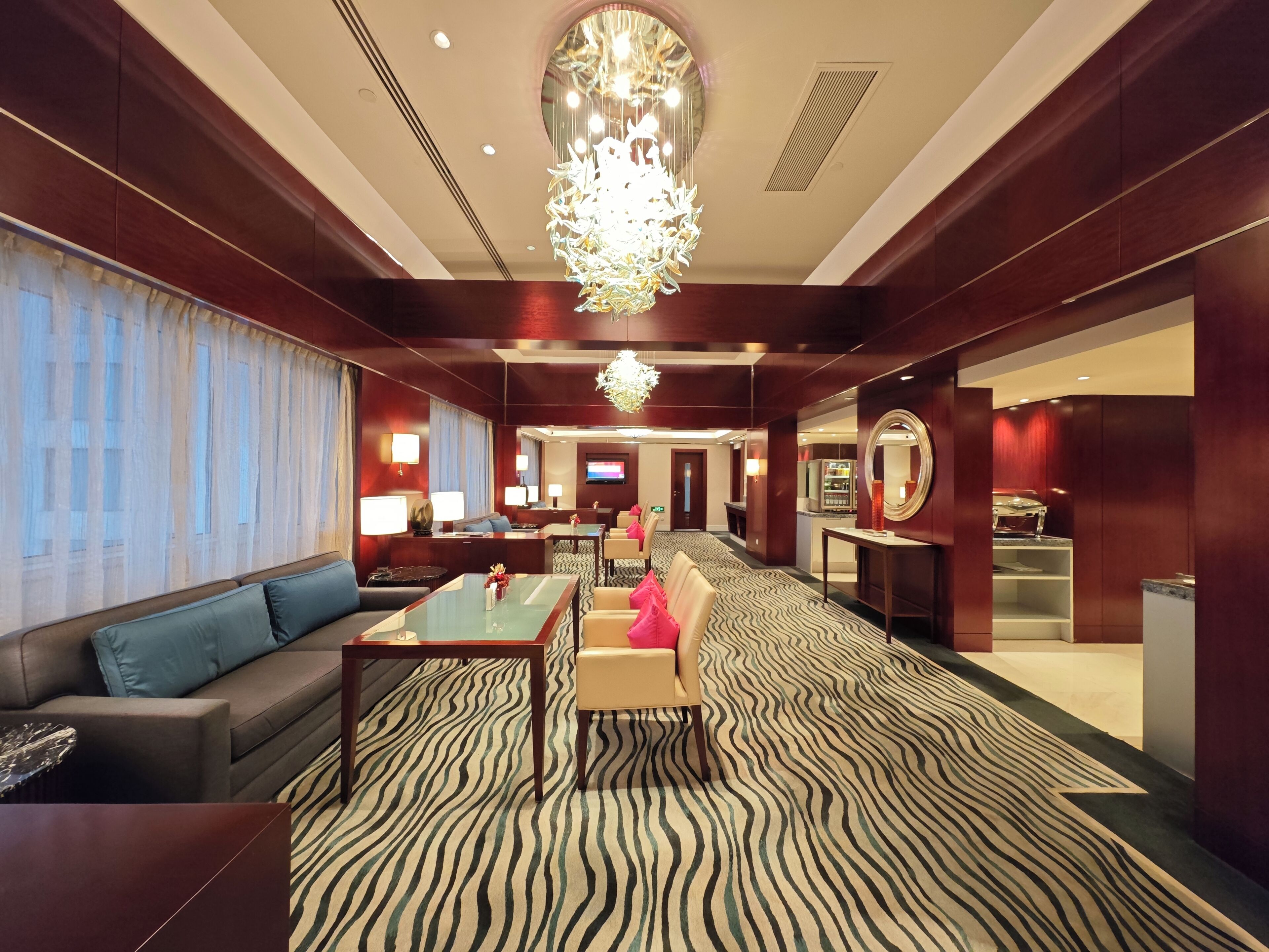 Um saguão de hotel com carpete listrado em preto e branco, um sofá, uma mesa e um lustre.