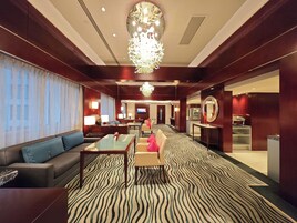 A hotel lobby with a zebra-striped carpet, a sofa, a table, and a chandelier.