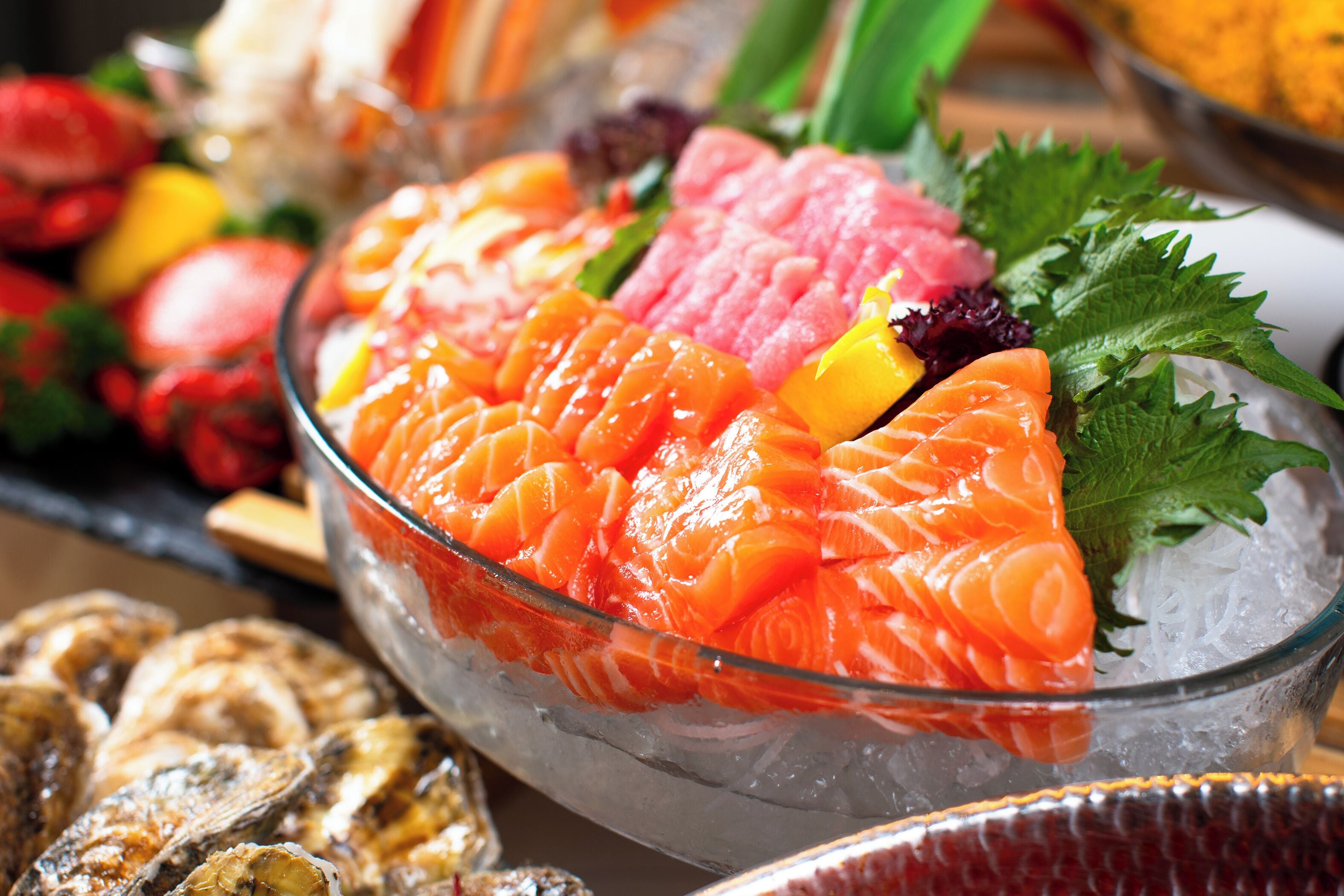 Un tazón de sushi con diferentes ingredientes, incluyendo salmón y otros mariscos, sobre una cama de hielo.