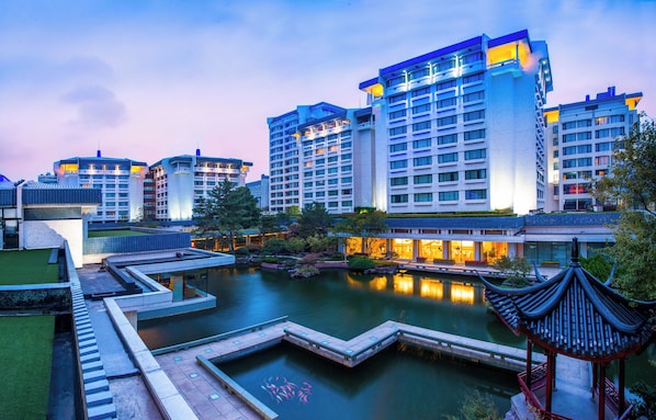 A modern hotel complex with multiple high-rise buildings, a central courtyard with a water feature, and traditional-style pavilions.