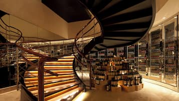Una scala a chiocciola con gradini in legno e ringhiere in metallo, che conduce a una cantina vinicola con bottiglie di vino ordinate.