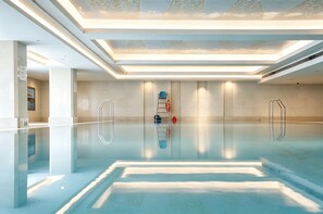 A modern indoor swimming pool with clear water, a glass floor, and a minimalist design. - The Dragon Hotel (Hangzhou)