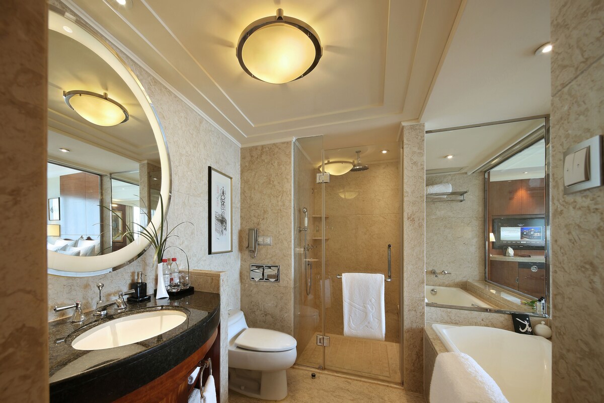 A modern bathroom with a large mirror, a sink, a toilet, a shower, and a bathtub.