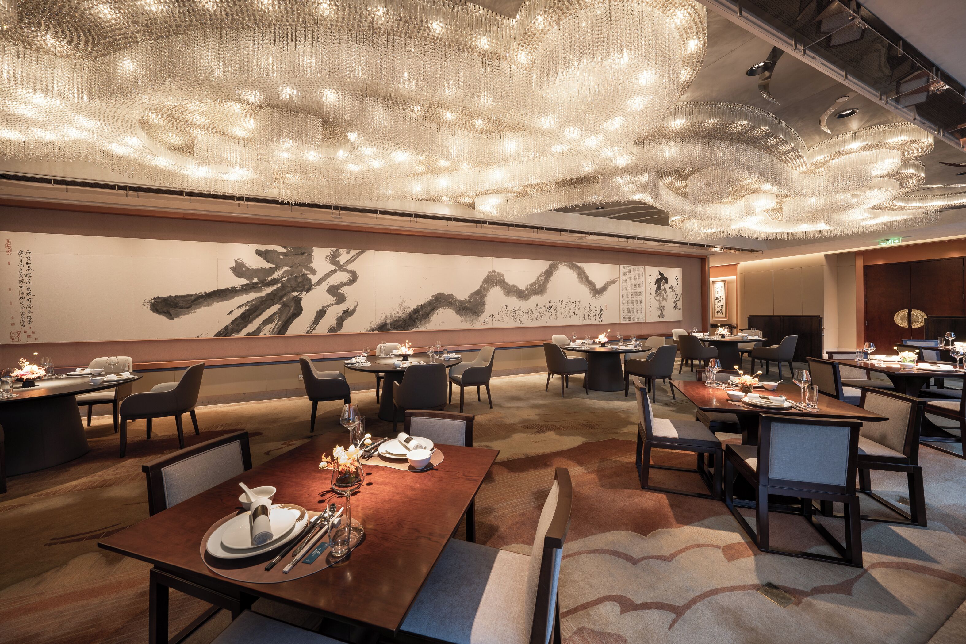 A modern dining area with multiple tables, chairs, and a large abstract painting on the wall.