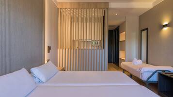 Habitación de hotel con dos camas, un separador de madera, un televisor y un espejo.
