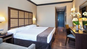 A hotel room with a large bed, a desk with a chair, a telephone, and a mirror.