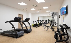 Une salle de sport équipée de tapis de course, de vélos d’appartement et d’appareils de musculation.