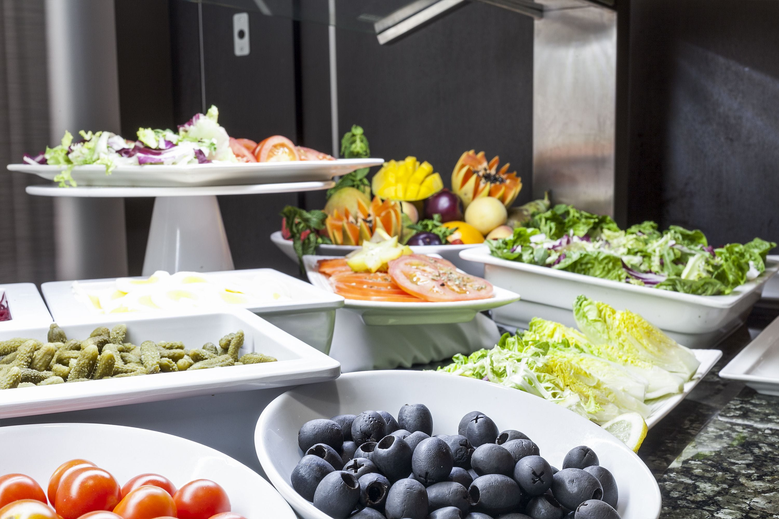 Un bufé con distintos alimentos, como ensaladas, frutas y verduras.