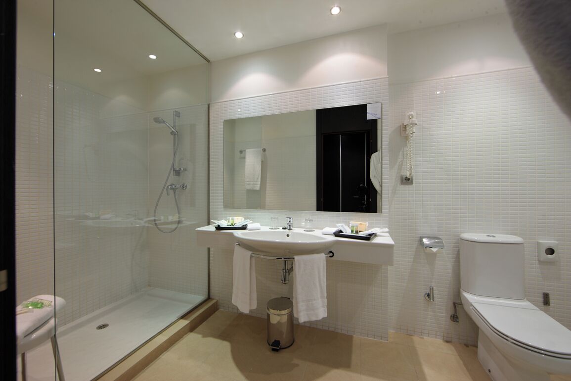 A modern bathroom with a glass-enclosed shower, a sink with a mirror above, and a toilet.