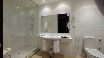 A modern bathroom with a glass-enclosed shower, a sink with a mirror above, and a toilet.