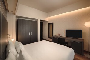 A modern hotel room with a large bed, a desk with a flat-screen TV, a wardrobe, and a mirror. - NH Collection Torino Santo Stefano (Turin)