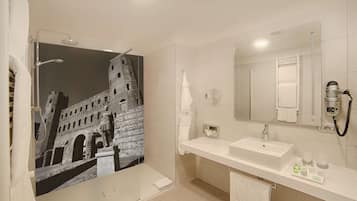 A modern bathroom with a large mirror, a shower with a glass door, and a sink with toiletries.