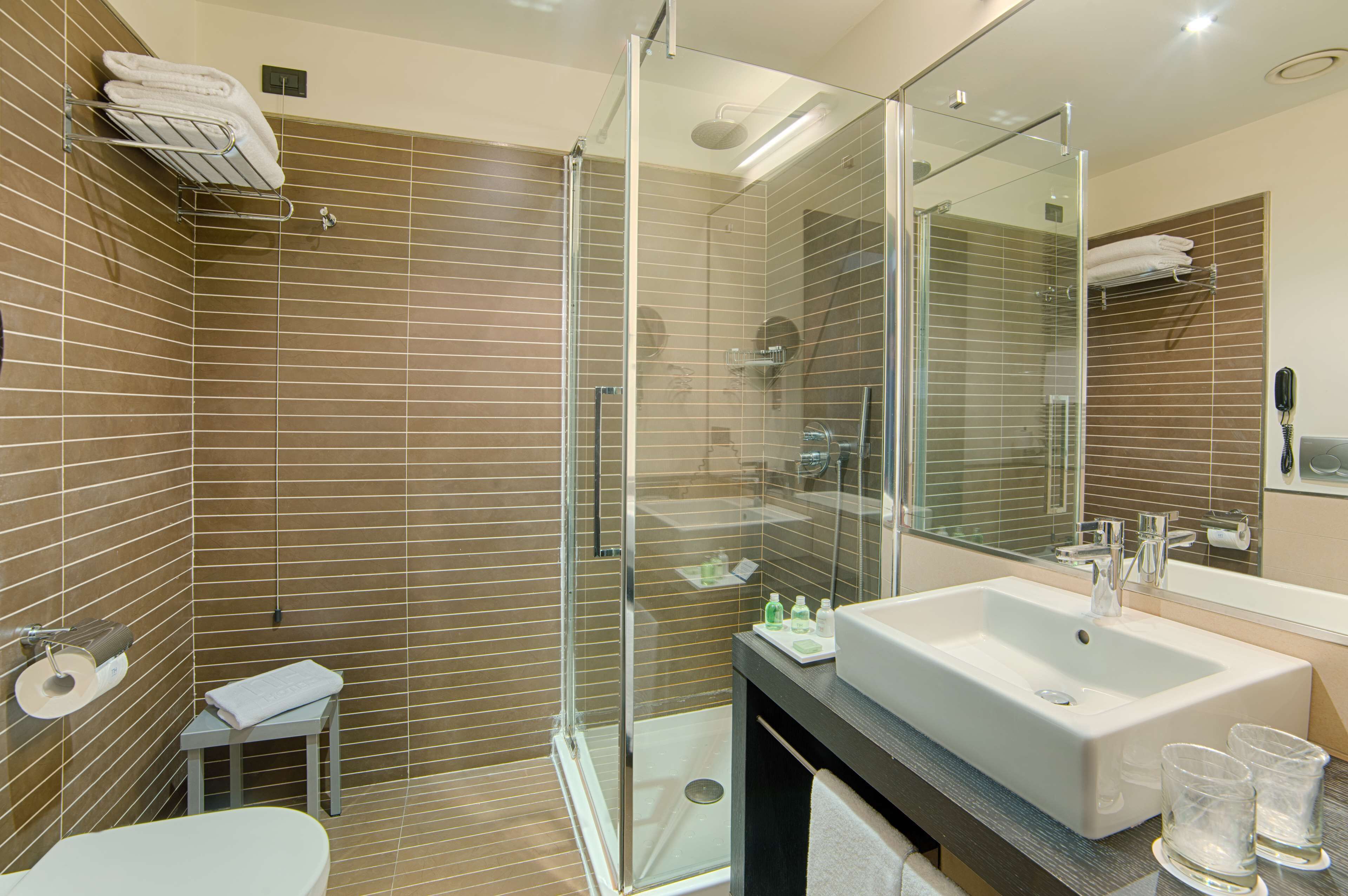 Un bagno moderno con cabina doccia in vetro, un lavandino capiente e uno specchio.