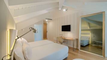 Una habitación de hotel moderna con una cama grande, un escritorio, un televisor de pantalla plana y un espejo.