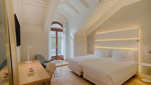 A modern hotel room with a wooden ceiling, a large bed, a desk with a chair, and a window with curtains. - NH Collection Torino Santo Stefano (Turin)