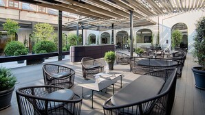 An outdoor patio area with wicker furniture, potted plants, and a modern architectural design. - NH Collection Torino Santo Stefano (Turin)