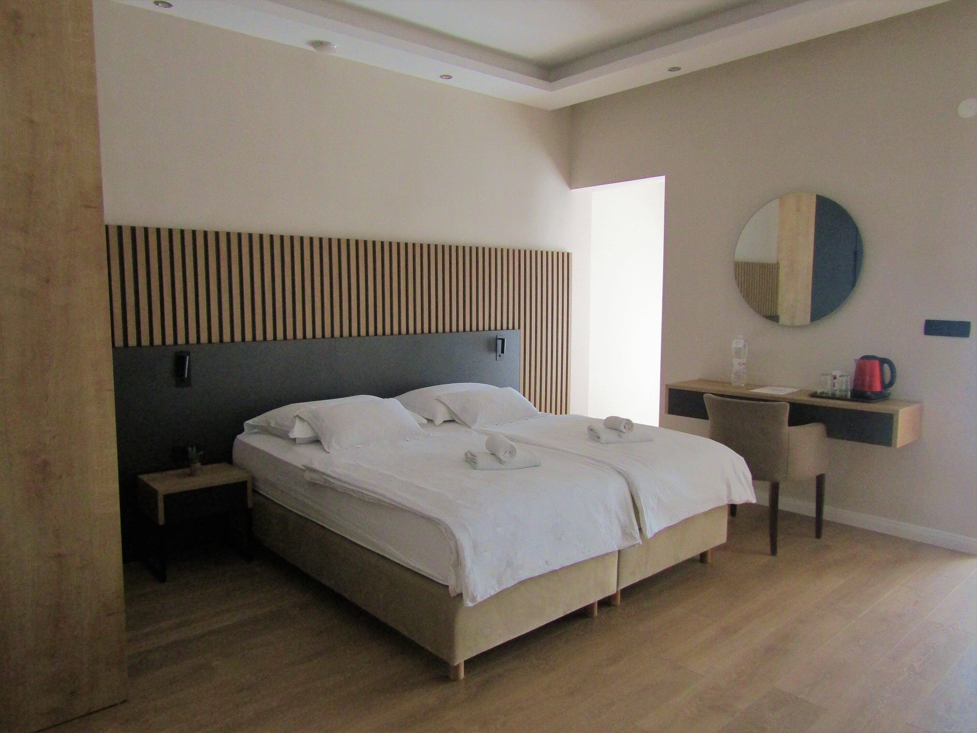 A modern hotel room with a large bed, a desk, and a chair.