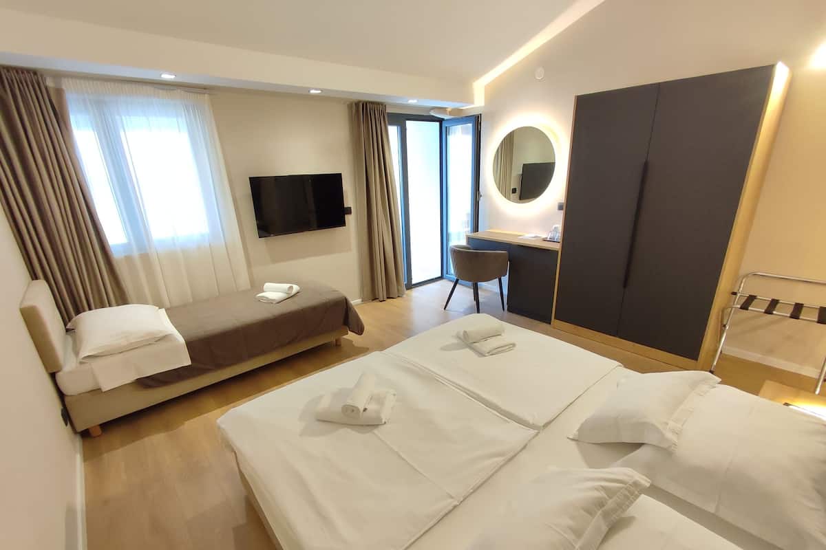 A hotel room with two beds, a desk, a chair, a TV, and a wardrobe.