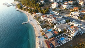 Vue aérienne d’une zone résidentielle côtière, avec des maisons, une plage et un port de plaisance.