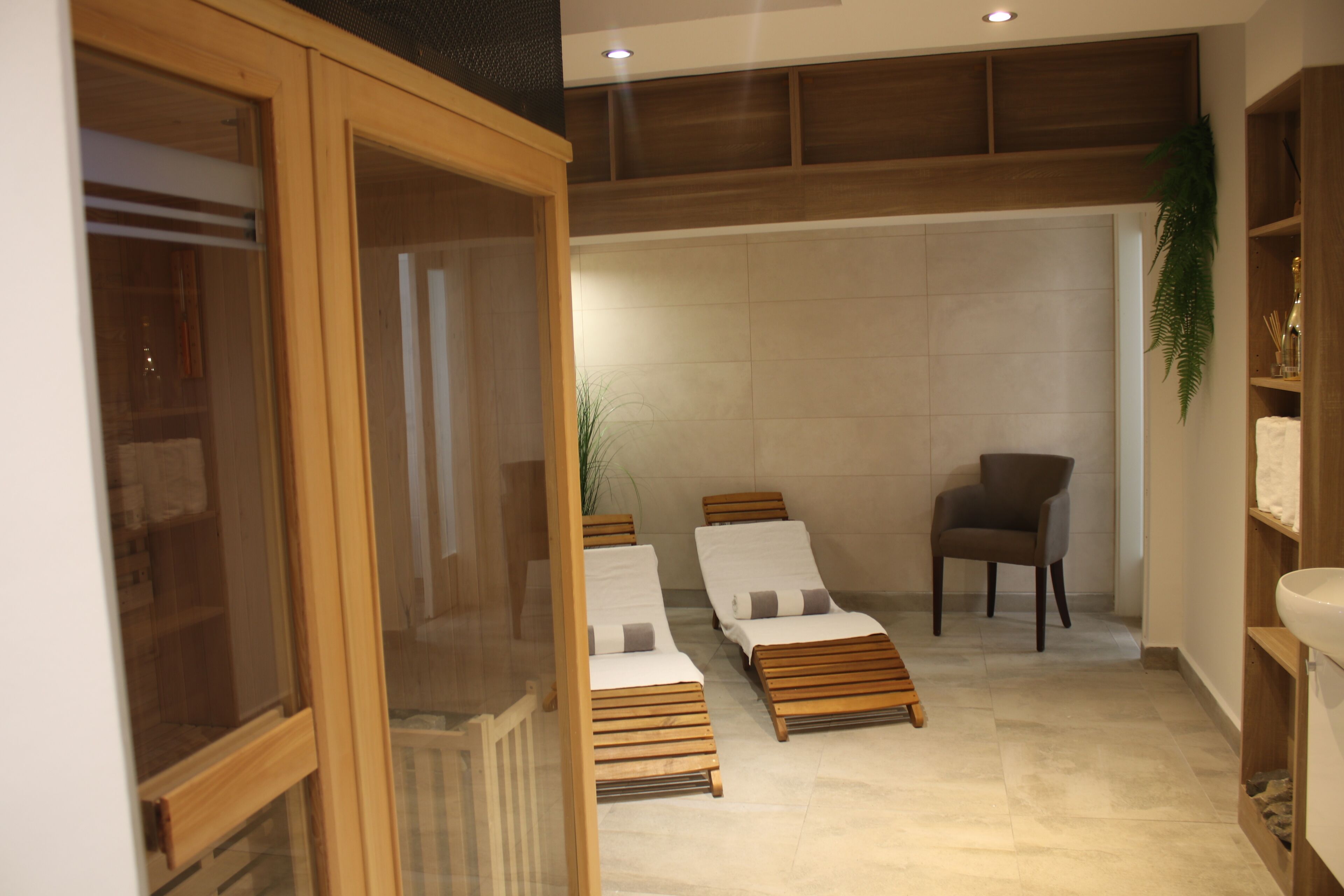 Un cuarto de spa con camastros de madera, una silla y un ventanal grande.