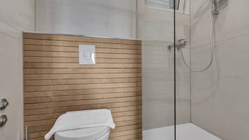Un baño moderno con pared de paneles de madera, inodoro blanco y zona de ducha con mampara de vidrio.