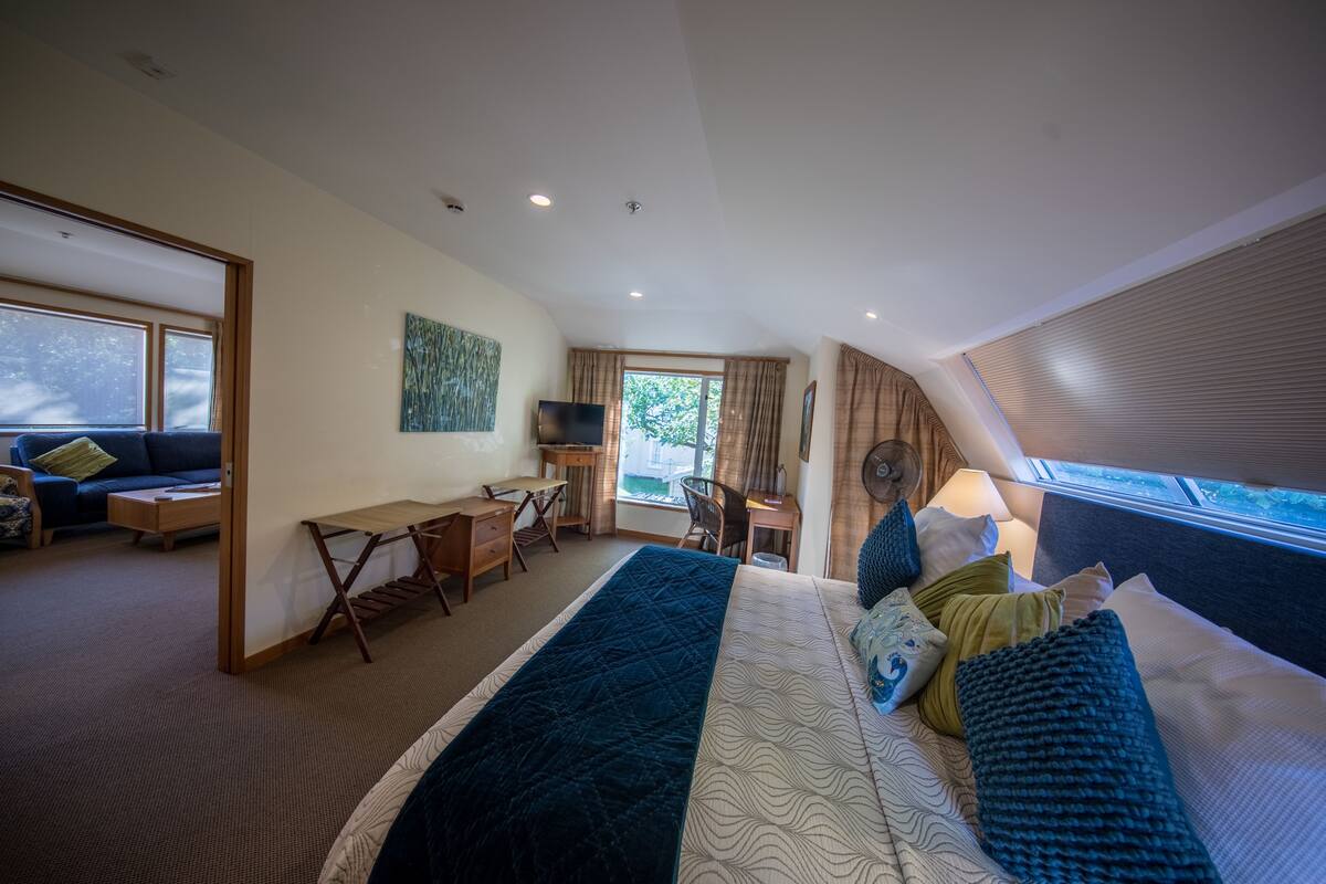 Una habitación de hotel moderna con una cama grande, un escritorio, una silla y un televisor.