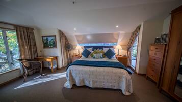 A bedroom with a large bed, a desk, a chair, and a wardrobe.