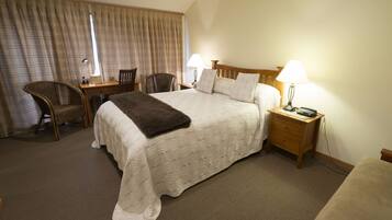 A hotel room with a large bed, two bedside tables with lamps, a chair, and a desk.