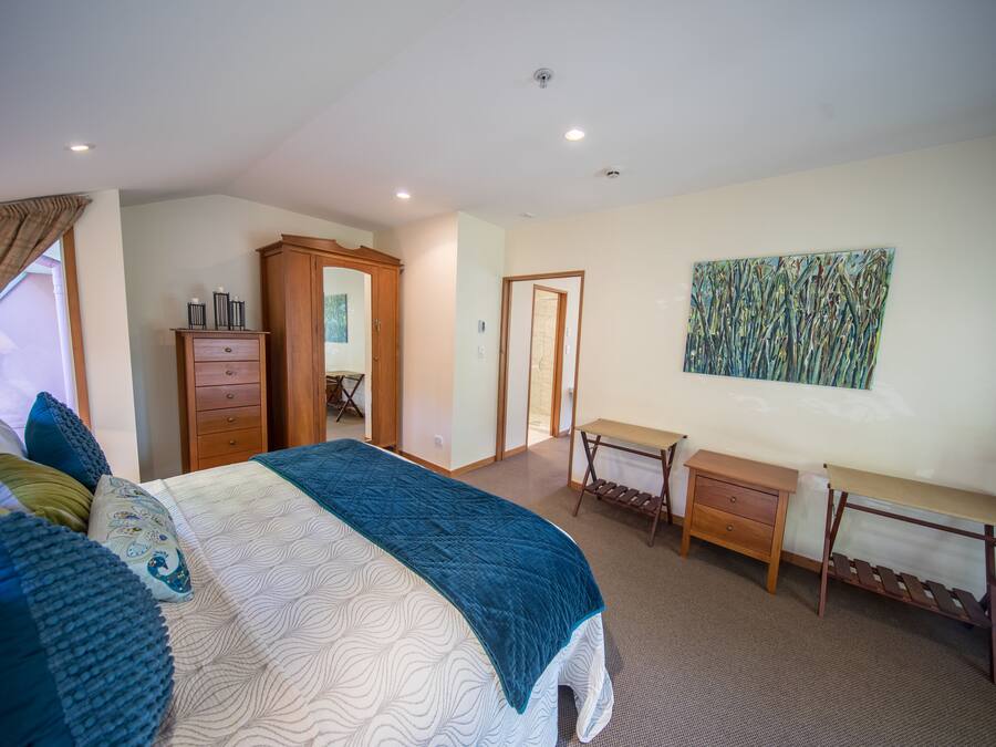 Um quarto com uma cama, cômoda de madeira, escrivaninha e uma cadeira.