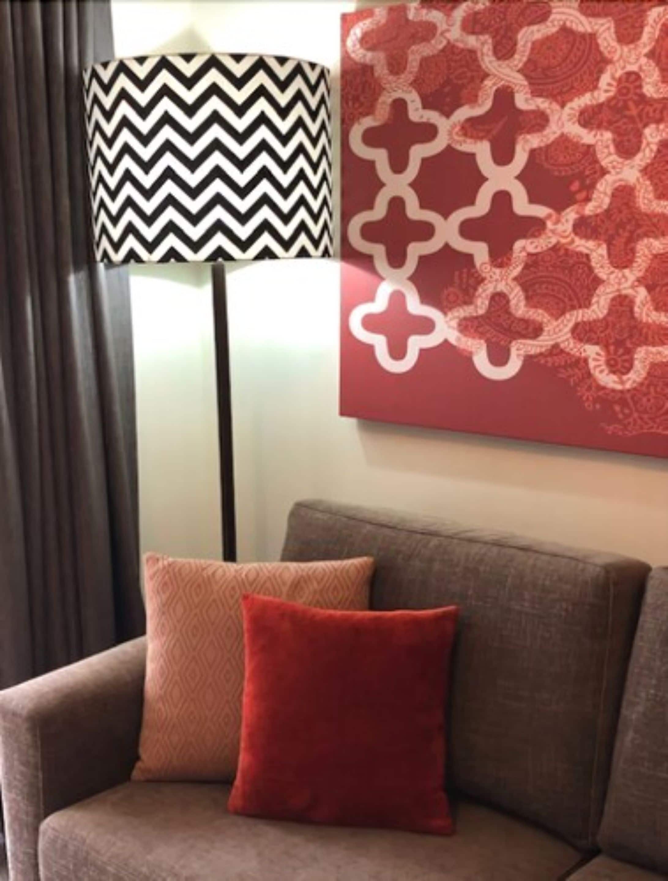 A living room with a sofa, a patterned lamp, and a decorative wall piece.