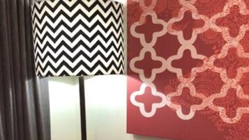 A living room with a sofa, a patterned lamp, and a decorative wall piece.