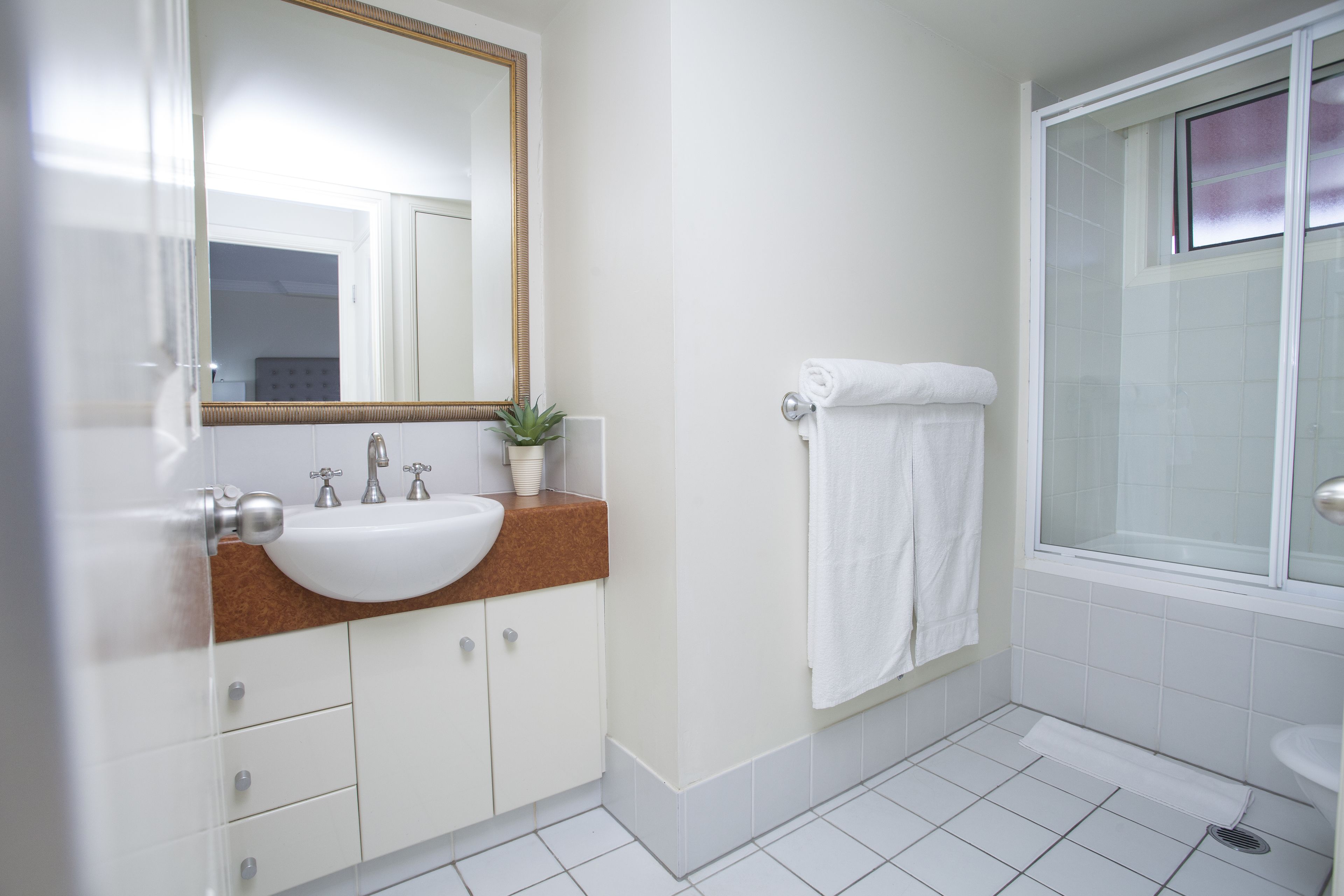 A bathroom with a white sink, mirror, and shower.