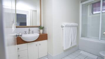A bathroom with a white sink, mirror, and shower.