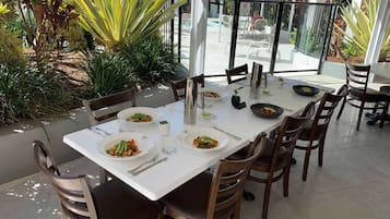An outdoor dining area with a white table set for four, surrounded by wooden chairs.