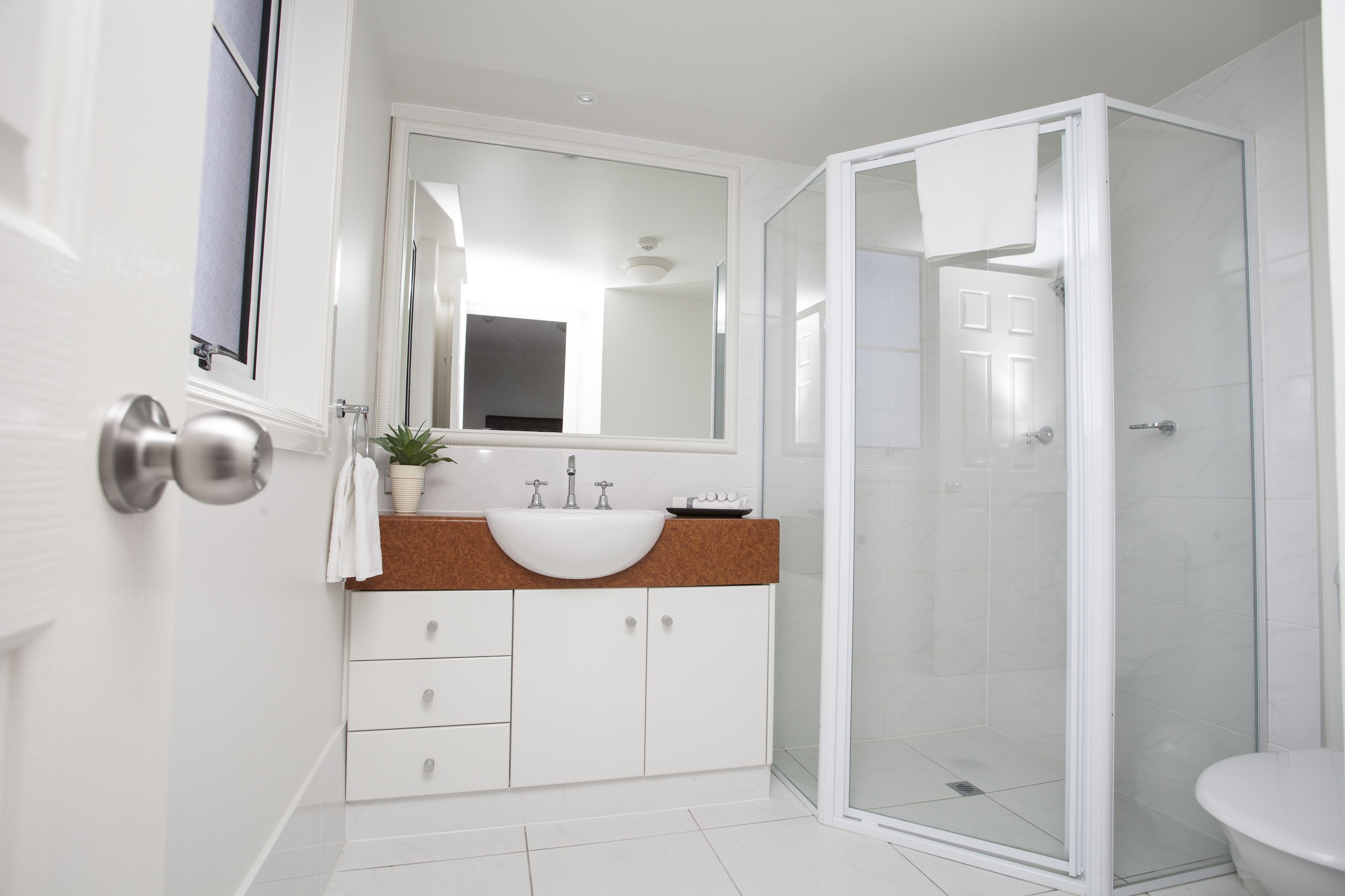 A modern bathroom with a white sink, a glass shower enclosure, and a large mirror above the sink.