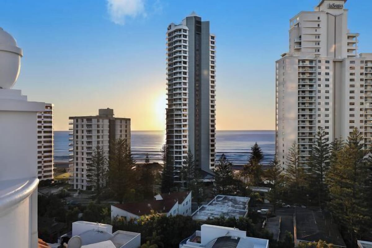 A high-rise building with a view of the ocean at sunset.