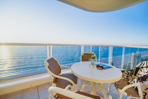 A balcony with a round table, chairs, and a view of the ocean. - Xanadu Main Beach Resort (Main Beach)
